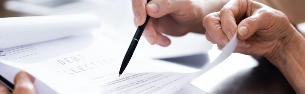 Panoramic crop of senior couple holding papers with debt collection lettering and pen